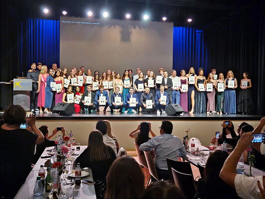 Absolventen der Erich-Bracher-Schule präsentieren ihre Abschlusszeugnisse auf der Bühne.