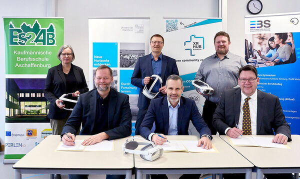 Sechs Personen bei der Unterzeichnung einer Kooperationsvereinbarung zur VR-Bildung, einige halten VR-Headsets.