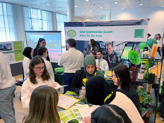 Stand der Übungsfirmen der Erich-Bracher-Schule auf einer Messe. Schülerinnen beraten Besucher und führen Verkaufsgespräche.