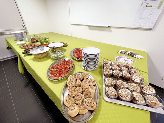 Verschiedenes Essen, Geschirr und Besteck auf Tischen mit grünen Tischdecken.