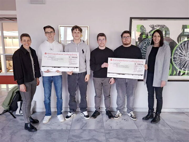 Eine Gruppe aus Schülern und Lehrern steht zusammen. Die Schüler halten zwei Zeremonieschecks der Kreissparkasse Ludwigsburg.