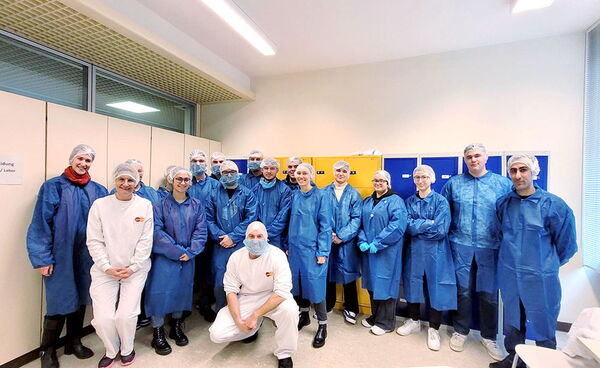 Schülern und Lehrkräften stehen in Schutzkleidung in einem Raum des Gewürzgroßhandels Hagesüd.