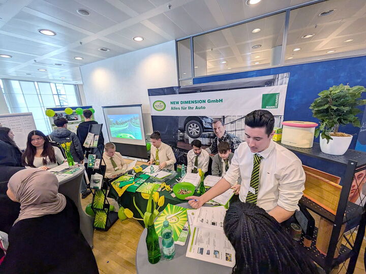 Am professionell gestalteten Stand der Übungsfirma New Dimension GmbH informieren Schülerinnen und Schüler der Erich-Bracher-Schule über ihr Angebot.