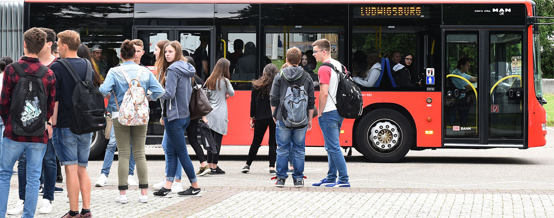 Schülergruppe der Erich-Bracher-Schule steigt an der Haltestelle in einen roten Linienbus Richtung Ludwigsburg ein.